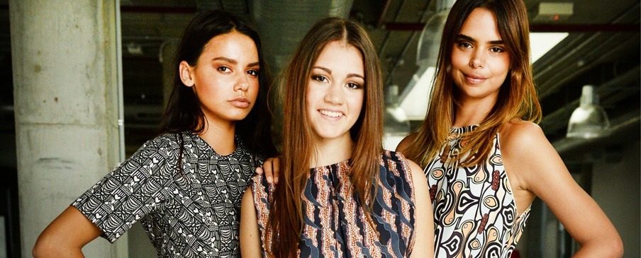 Pictured are Australian Indigenous Fashion Week ambassadors all wearing AKIN dresses, from left Lilla Conradson wearing the Comb-print dress created by Hayley Elasesser and Sharon Phineasa; Indigenous Model Search finalist Sinead Grehan (centre) in a Bushfire-print created by Margaret Mara and Samantha Delgos; and Samantha Harris wearing the Cassowary-print dress created by Napolean Oui and Georgia Grainger. Image from QUT: Dan Himbrechts, AAP.